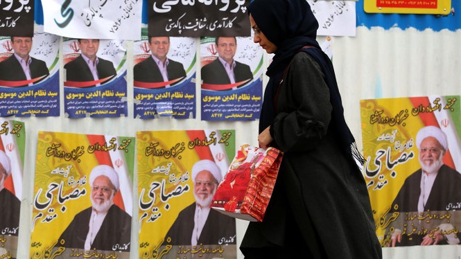إيرانية تمر بملصقات إنتخابية في أحد شوارع طهران