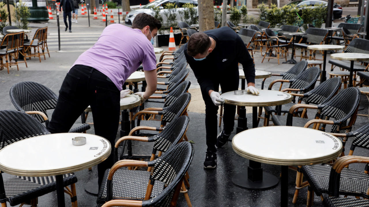 موظفون يقومون بتنظيف الطاولات في الشرفة الخارجية، في باريس في 11 أيار/مايو 2021