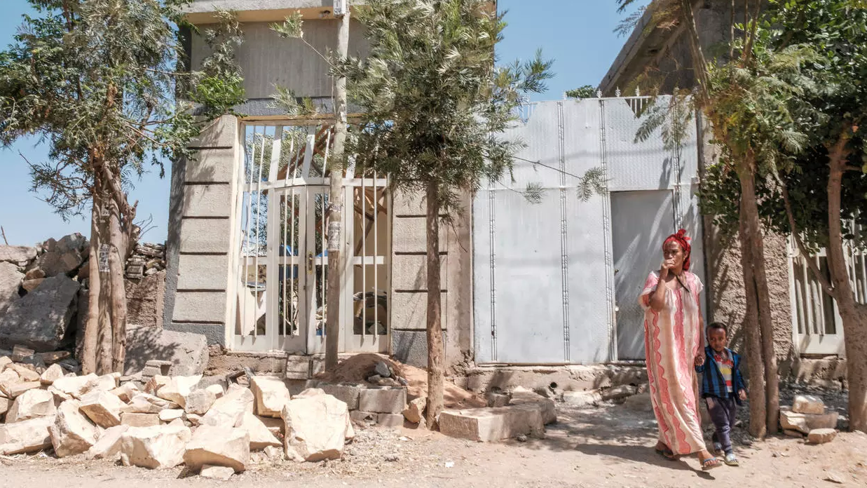 إمرأة وطفل أمام منزل مدمر في إقليم تيغراي