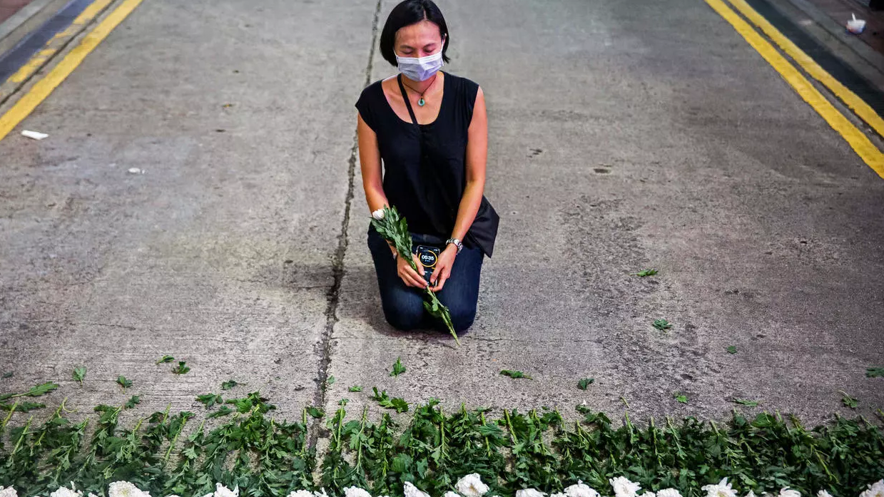 فنانة تحيي ذكرى تيان أنمين بوضع زهور بيضاء على الطريق في هونغ كونغ