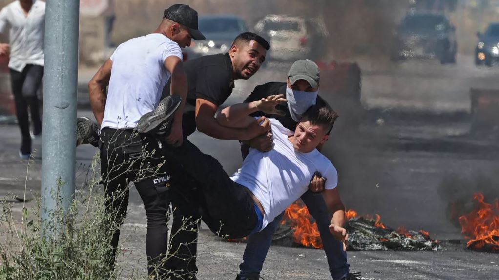 فلسطينيون ينقلون مصابا خلال مواجهات مع قوات الأمن الإسرائيلية بالقرب من حاجز حوارة جنوب مدينة نابلس بالضفة الغربية المحتلة
