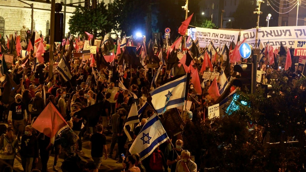 اسرائيليون يلوحون بالأعلام خلال مظاهرة بالقرب من مقر إقامة رئيس الوزراء الإسرائيلي بنيامين نتانياهو في القدس، في 31 أكتوبر 2020 ، للمطالبة باستقالته بسبب قضايا فساد
