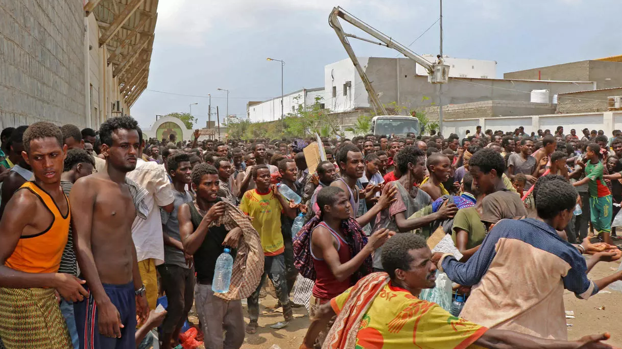 مهاجرون أفارقة يحصلون على المياه والطعام في ملعب لكرة القدم في مدينة عدن اليمنية
