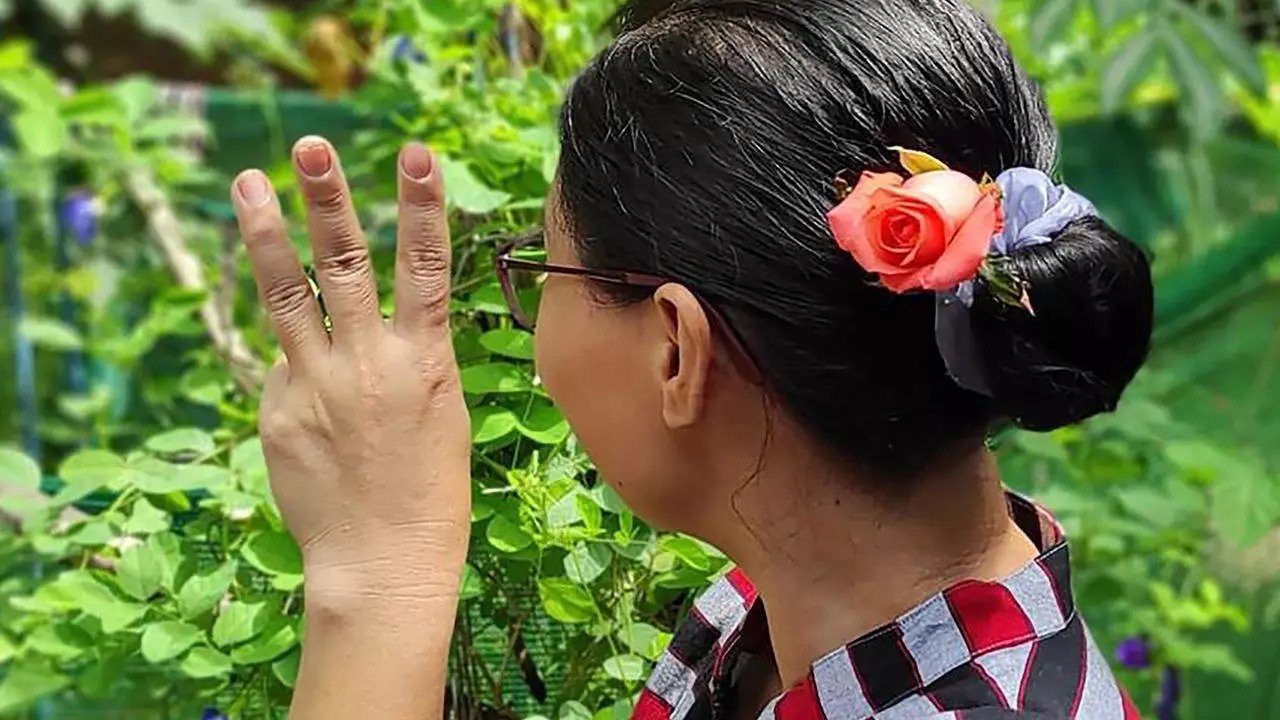 ناشطة بورمية مؤيدة للديموقراطية تضع زهرة في شعرها تكريماً للزعيمة السابقة أونغ سان سو تشي وترفع إشارة الثلاثة أصابع التي ترمز إلى المقاومة في صورة حصلت عليها فرانس برس من مصدر مجهول على فيسبوك.