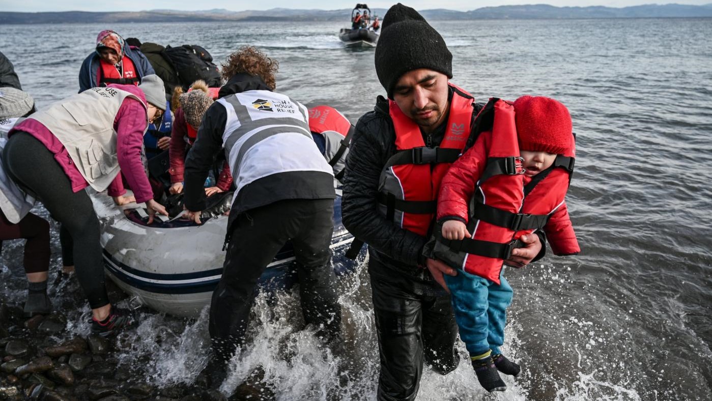 أعضاء المنظمات غير الحكومية يساعدون اللاجئين على النزول من زورق أثناء هبوطه على شاطئ جزيرة ليسبوس اليونانية في 28 فبراير 2020