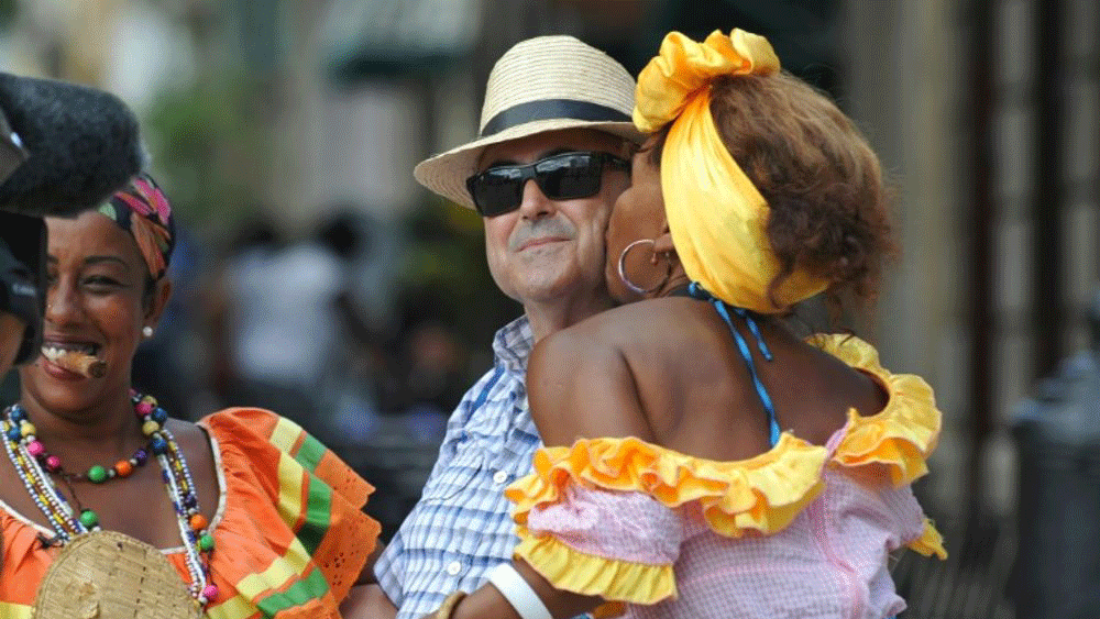 سائح أمريكي تقبله امرأة كوبية ترتدي زيًا تراثياً في أحد شوارع هافانا القديمة في 18 أيلول/سبتمبر 2015