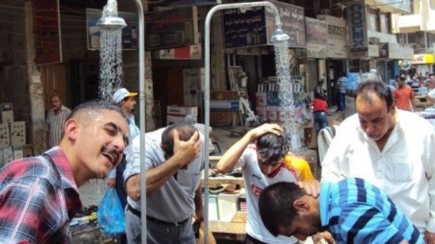 عراقيون يتقون حرارة الجو بحمامات مفتوحة في أحد شوارع بغداد
