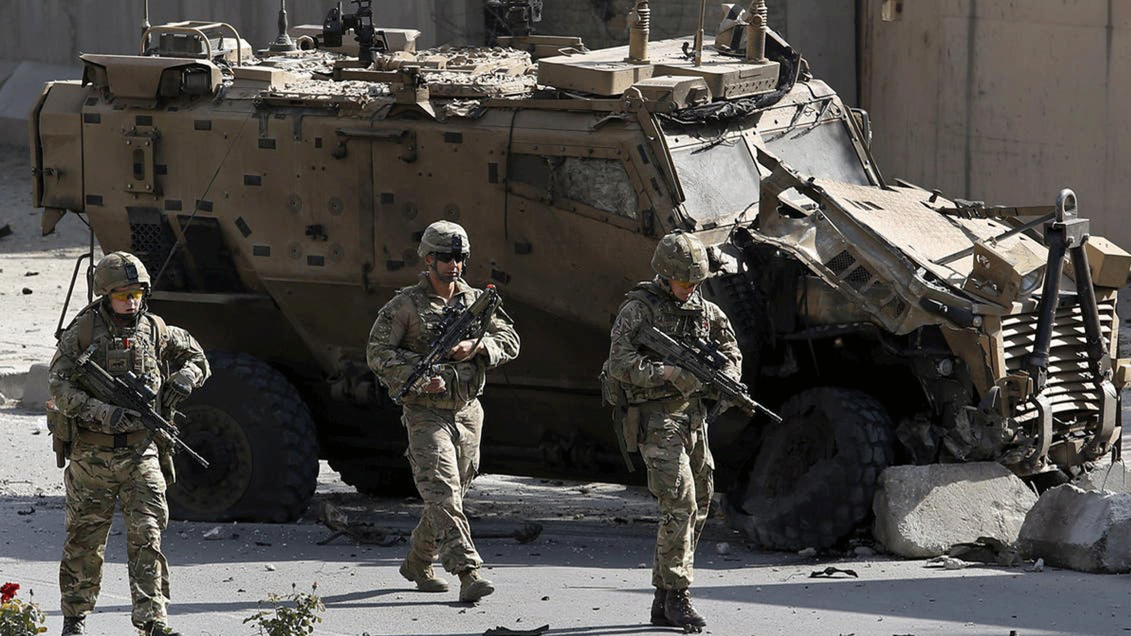 جنود من الناتو يسيرون أمام مركبة عسكرية متضررة لحلف شمال الأطلسي، في موقع تفجير انتحاري بسيارة مفخخة في كابول، أفغانستان، 11 تشرين الأول/ أكتوبر 2015