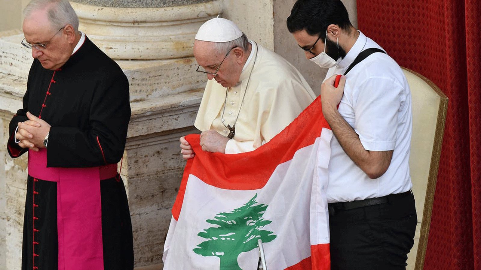 (من اليسار) المونسنيور ليوناردو سابينزا والبابا فرنسيس وكاهن لبناني يحمل علم لبنان يصلون من أجل لبنان خلال الحضور العام المحدود للبابا في ساحة سان داماسو بالفاتيكان في 2 أيلول/ سبتمبر 2020.