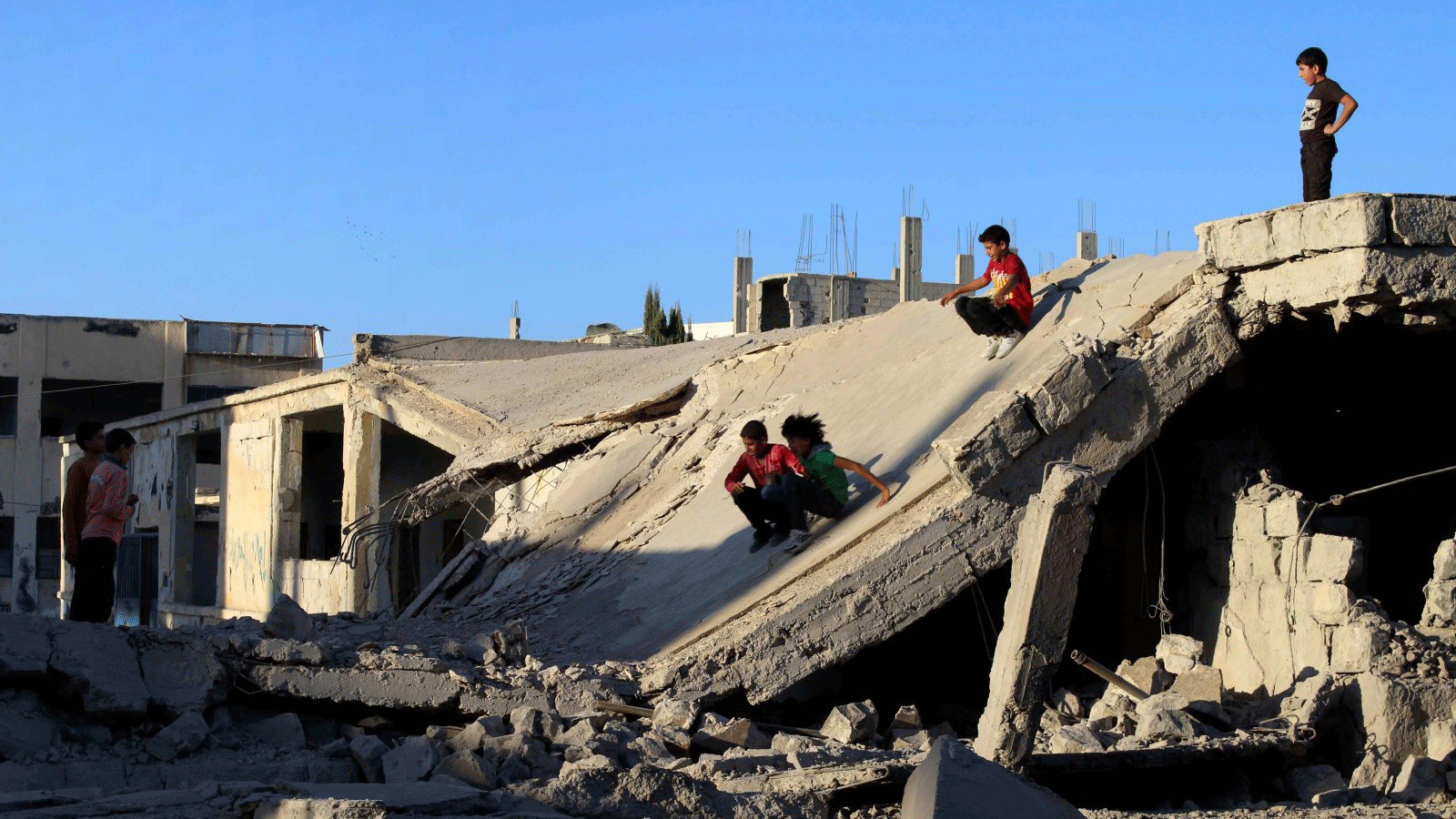 أطفال سوريون ينزلقون على أنقاض مبنى مدمر في مدينة درعا الخاضعة لسيطرة المعارضة في جنوب غرب سوريا، 12 أيلول/سبتمبر 2016