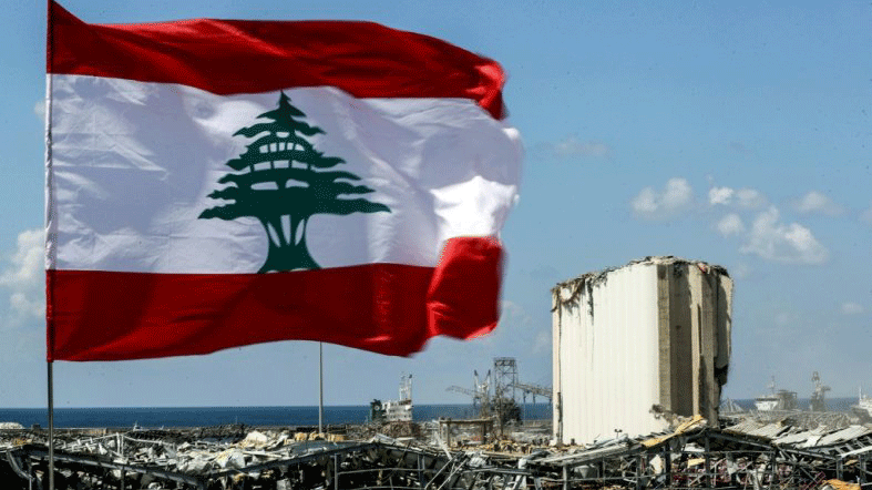 العلم اللبناني وفي الخلفية ركام مرفأ بيروت كما بدا يوم 4 آب/أغسطس 2020