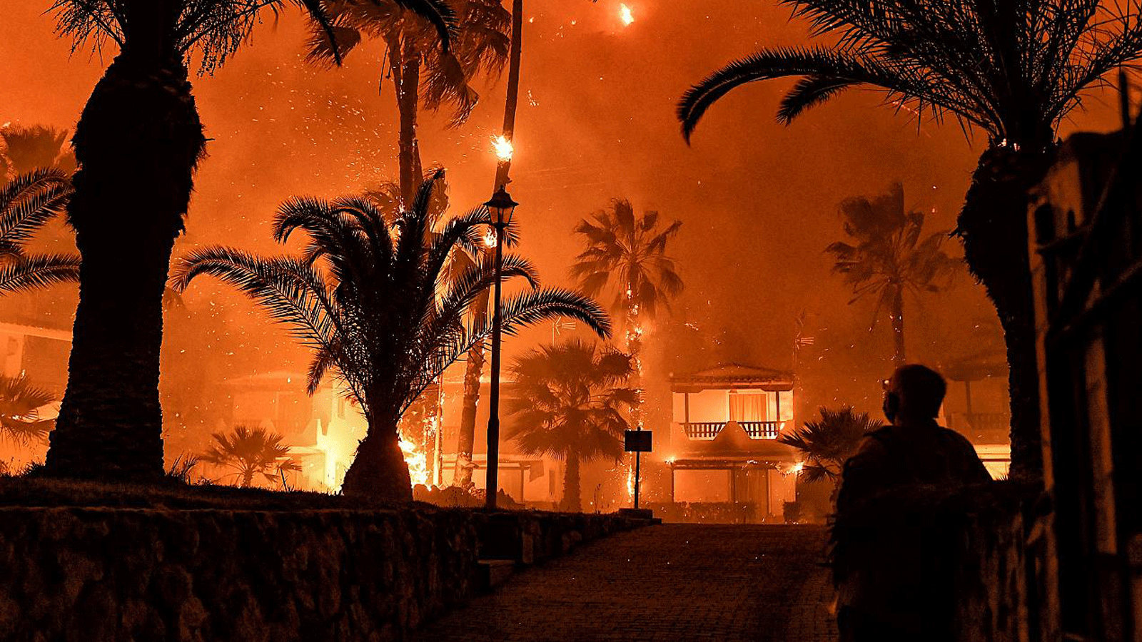 رجل يقف أمام حريق هائل في شينوس، غرب أثينا، اليونان. 19 أيار/مايو 2021