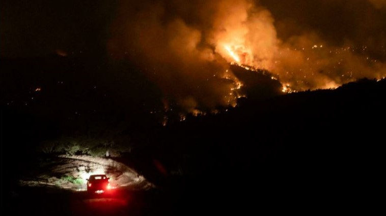 سيارة في قرية فافاتسينيا في منطقة لارنكا بينما تشتعل الحرائق على التلال في 3 يوليو 2021