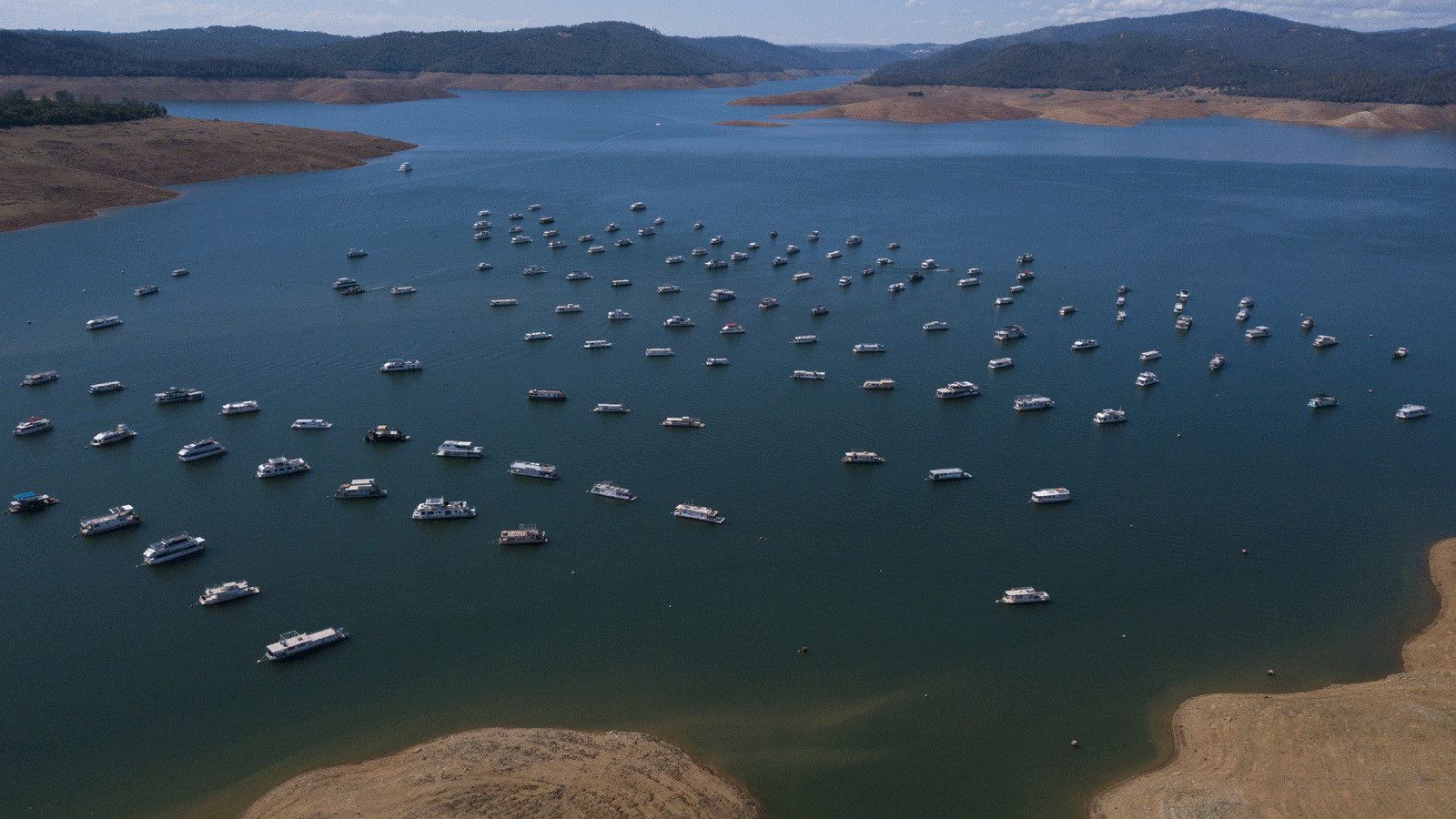 صورة جوية لمراكب ترسو على ضفاف خزان بحيرة أوروفيل التي تعاني انخفاضاً بمستويات المياه خلال حالة الطوارئ بسبب الجفاف في أوروفيل، كاليفورنيا