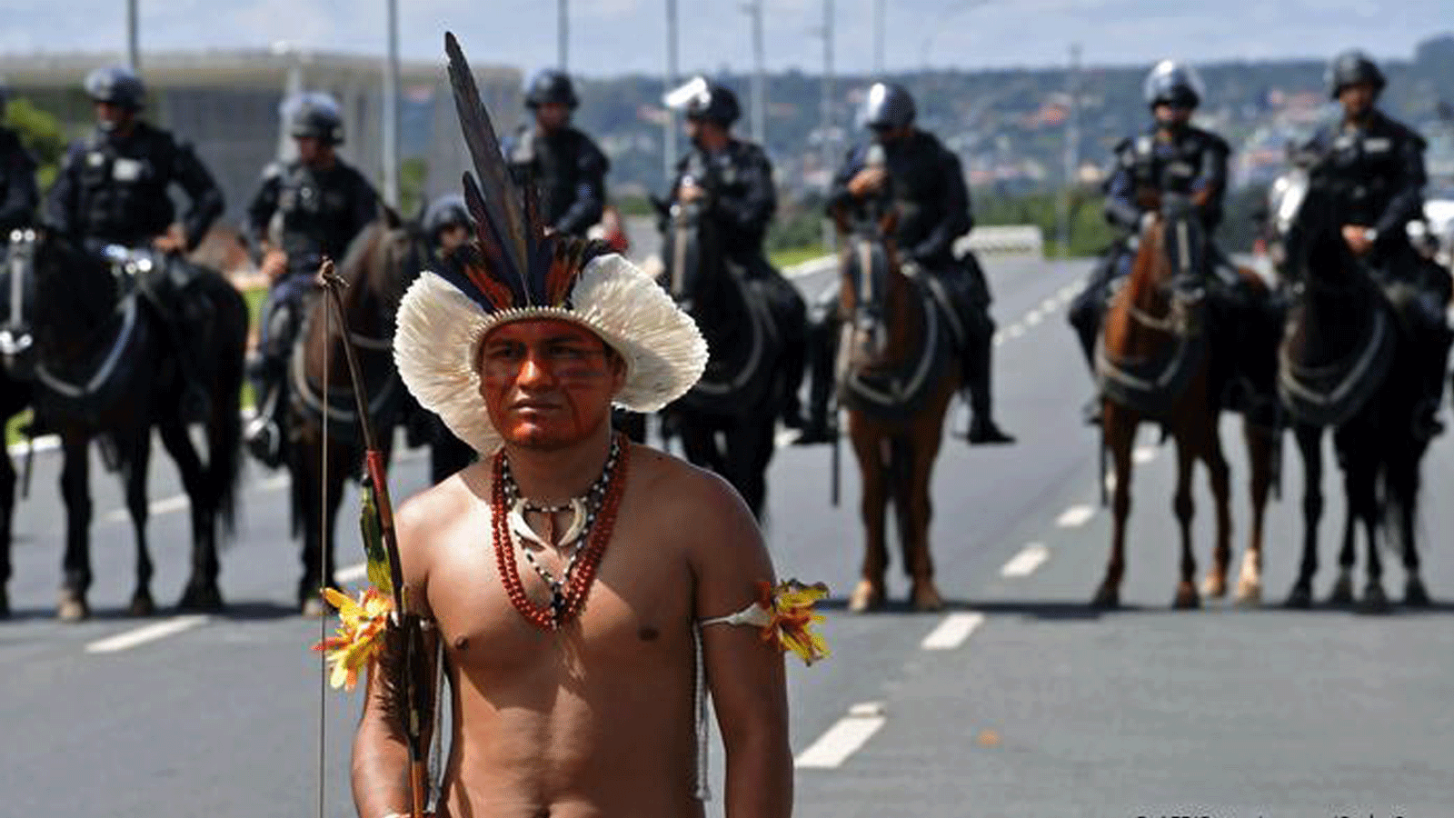متظاهرون بالزي التقليدي رسم بعضهم شريطة حمراء لتمثيل إراقة دماء السكان الأصليين. (صورة أرشيفية)