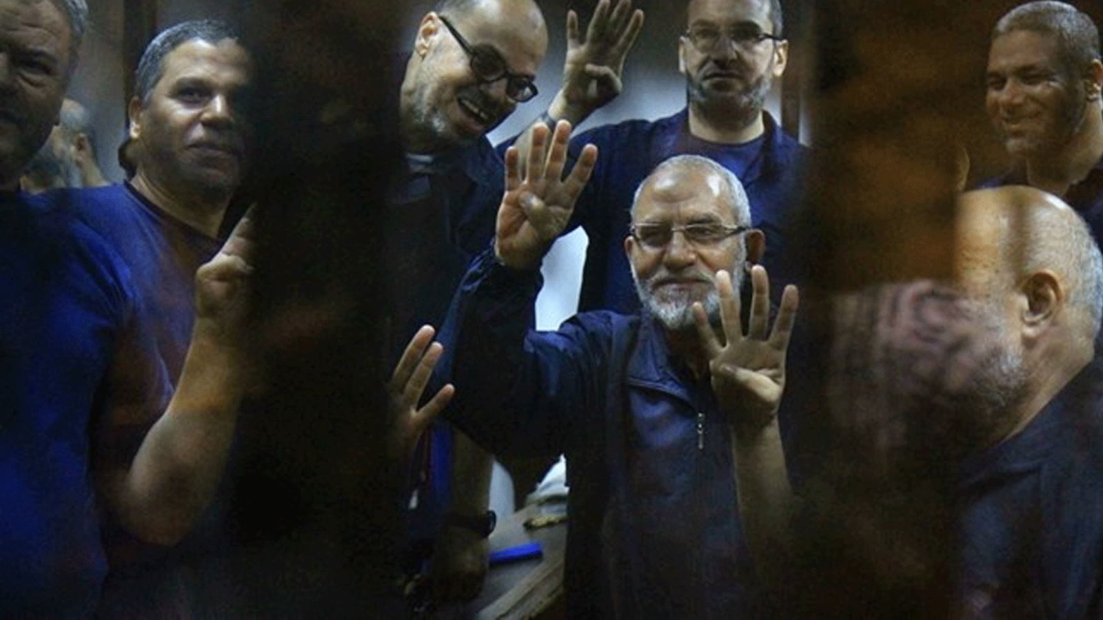 المرشد الأعلى للإخوان المسلمين محمد بديع (وسط) يُشير برمز الأصابع الأربعة المعروف باسم 