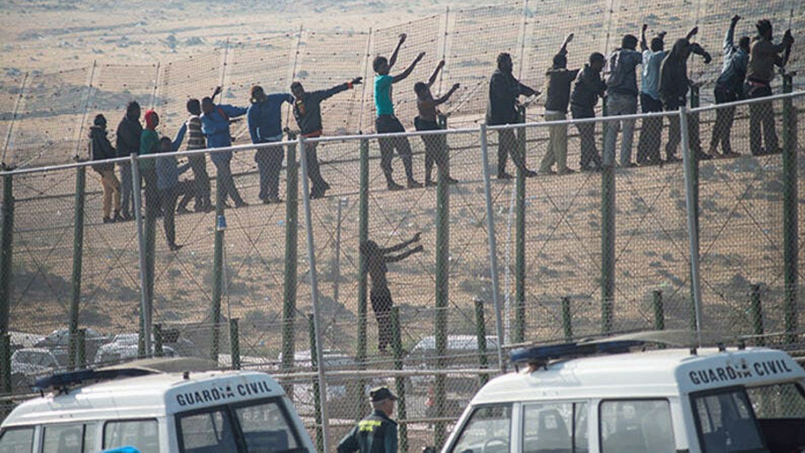 مهاجرون يقفون فوق سياج حدودي يفصل المغرب عن جيب مليلية الإسباني في 1 مايو 2014