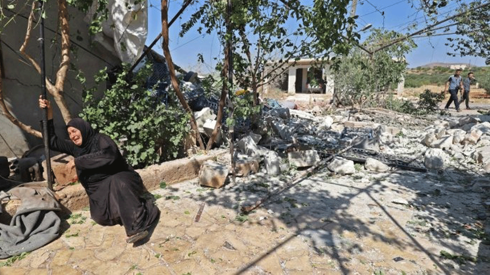 امرأة سورية بالقرب من أنقاض منزل دمره قصف مدفعي للنظام على قرية إبلين بمحافظة إدلب شمال غرب سوريا التي تسيطر عليها المعارضة. بتاريخ 22 تموز/ يوليو 2021