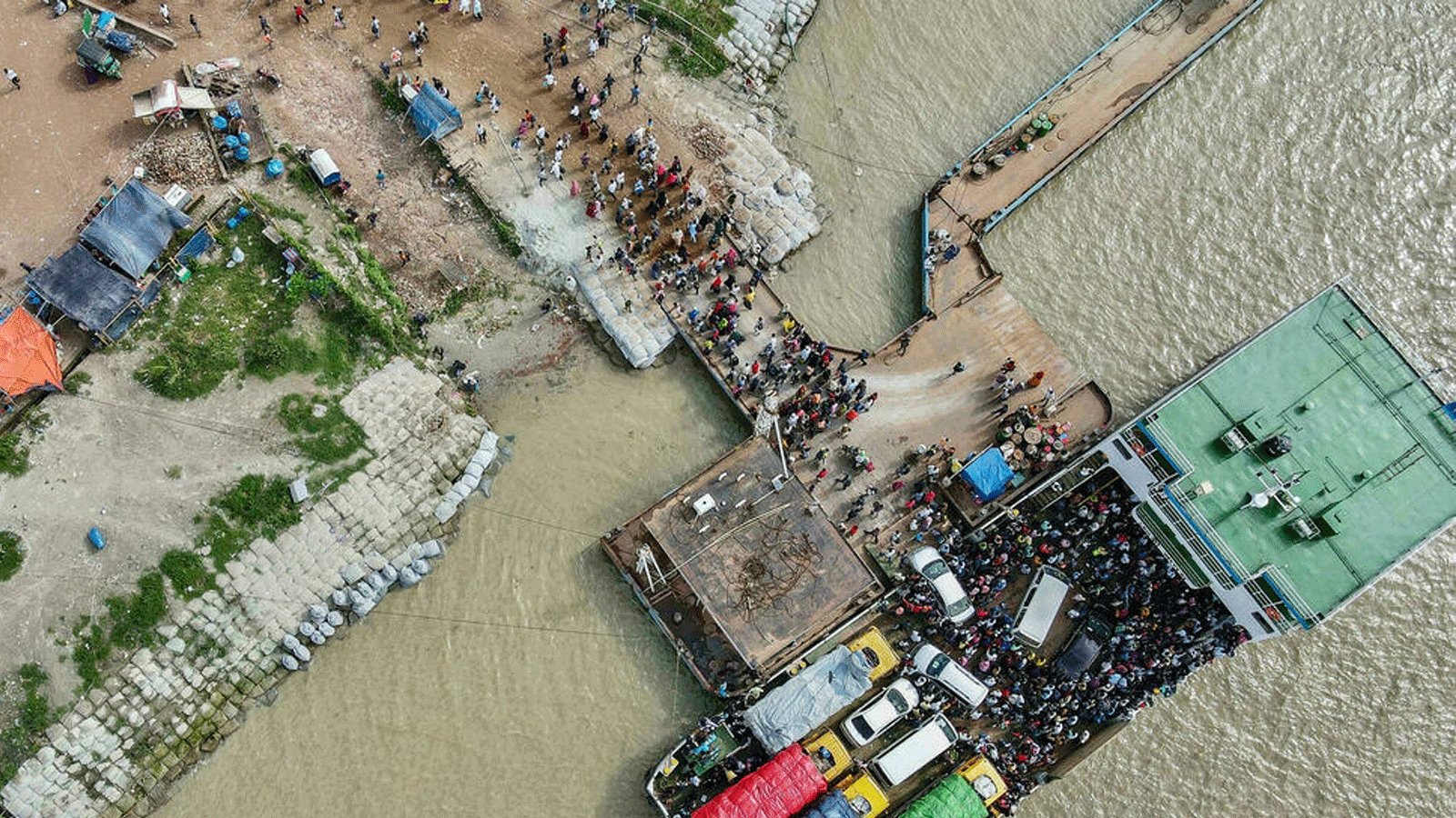 أشخاص ينزلون من العبارة للعودة إلى العمل حيث خففت حكومة بنغلاديش من إغلاق جميع المصانع الموجهة للتصدير. بتاريخ 31 تموز/ يوليو 2021