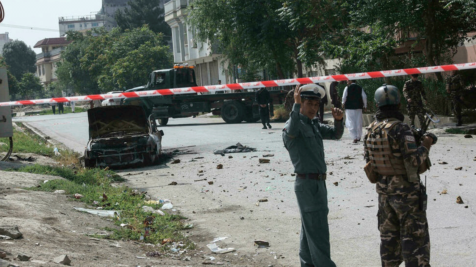 رجال أمن أفغان خلال نوبة حراسة بالقرب من مركبة متفحمة أطلقت منها صواريخ سقطت بالقرب من القصر الرئاسي الأفغاني في 20 تموز/يوليو 2021