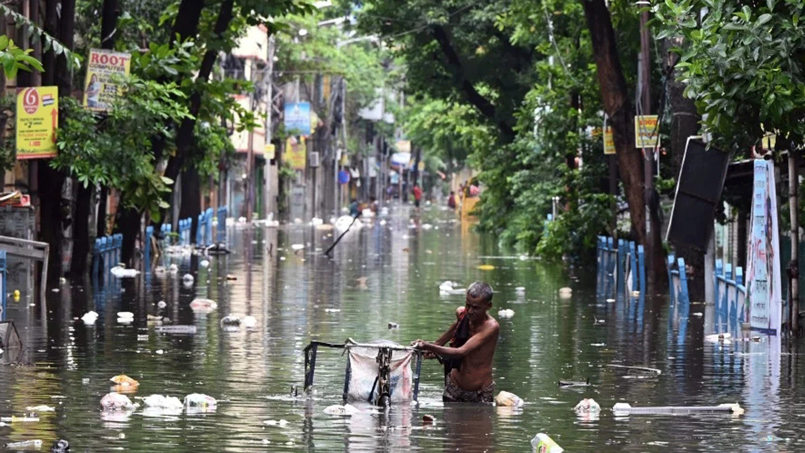 رجل يدفع شاحنته ثلاثية العجلات عبر مياه الفيضانات بعد هطول الأمطار في كولكاتا. بتاريخ 31 تموز/ يوليو 2021