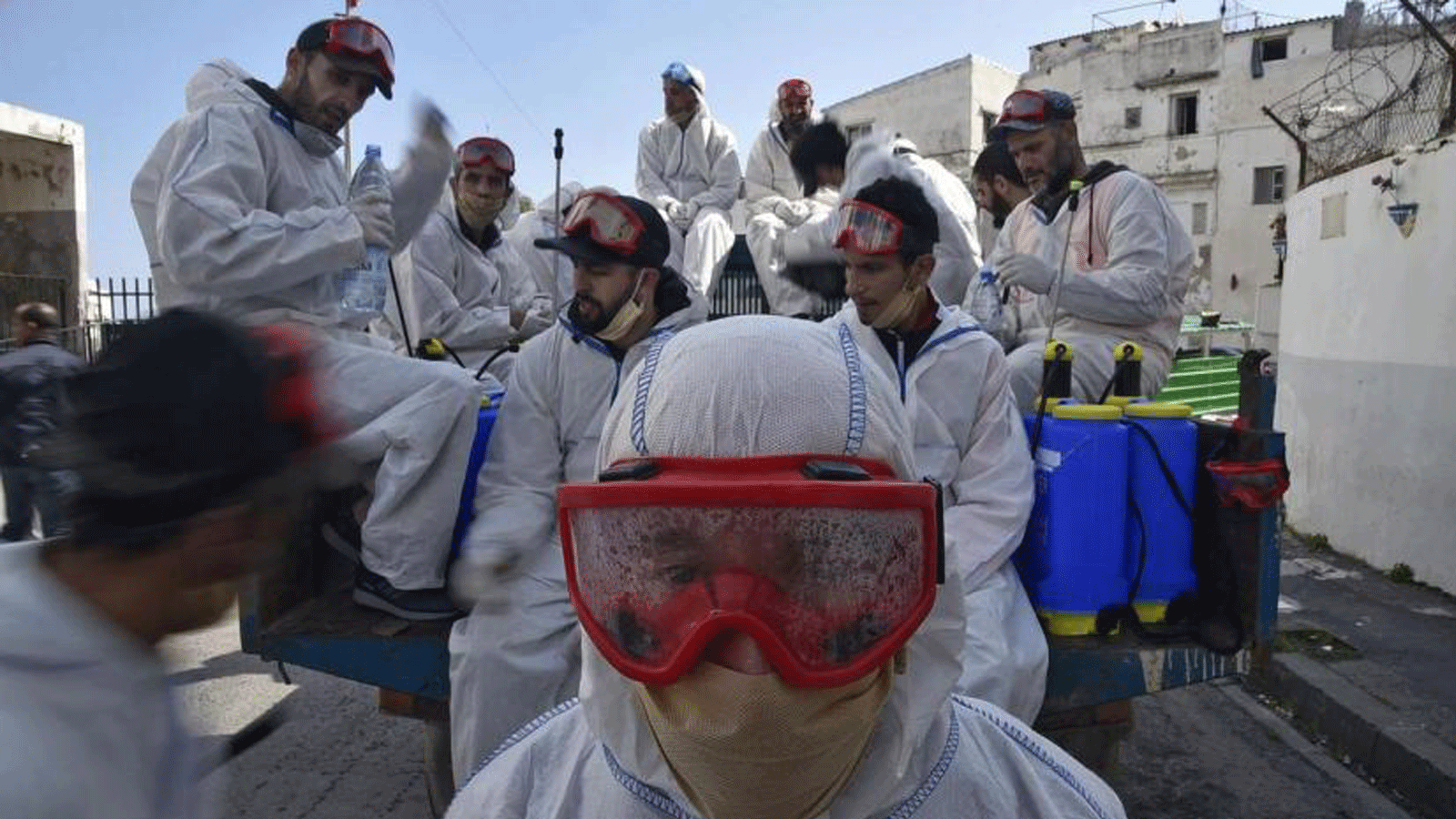 عمال البلدية يرتدون ملابس واقية يستريحون أثناء تأدية واجبهم لتطهير الشارع أثناء تفشي جائحة كوفيد -19 في منطقة باب الواد بالعاصمة الجزائرية الجزائر في 9 نيسان/أبريل 2020
