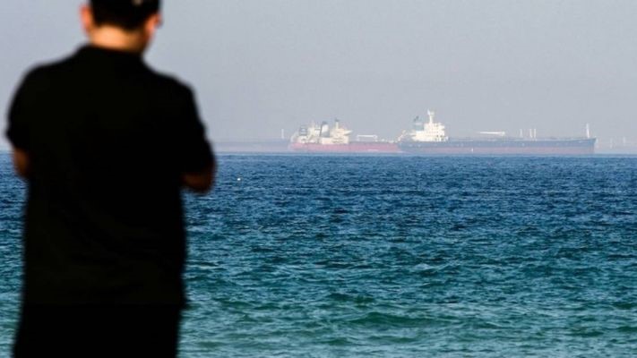رجل يشاهد ناقلات النفط على بعد مسافة من عمان
