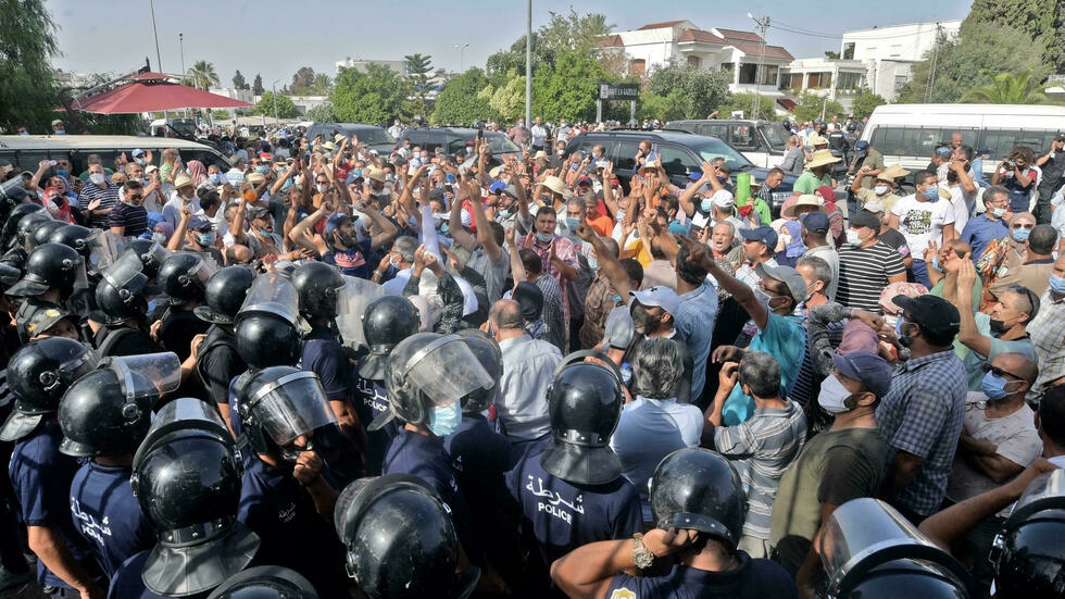 ضباط الأمن التونسيون يصدون المتظاهرين أمام مبنى البرلمان بعد أن علق الرئيس قيس سعيد المجلس التشريعي. بتاريخ 26 تموز/ يوليو 2021