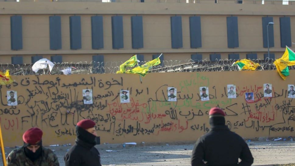 صور لمقاتلين من كتائب حزب الله العراقي معلقة على جدار السفارة الأميركية في بغداد في 1 يناير 2020