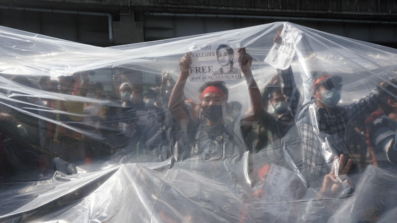 متظاهرون يقفون تحت غطاء بلاستيكي للحماية من خراطيم المياه التابعة للشرطة أثناء مشاركتهم في مظاهرة ضد الانقلاب العسكري في يانغون. بتاريخ 9 شباط/ فبراير 2021