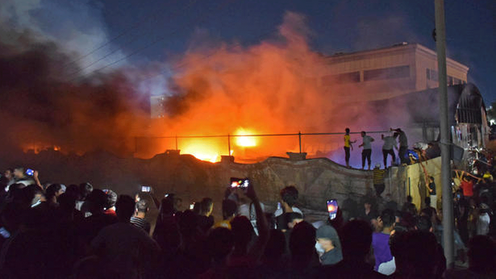 مواطنون يصورون ألسنة اللهب في حريق جناح عزل فيروس كورونا بمستشفى الحسين/ مدينة الناصرية جنوب العراق. مساء 12 يوليو/ تموز 2021