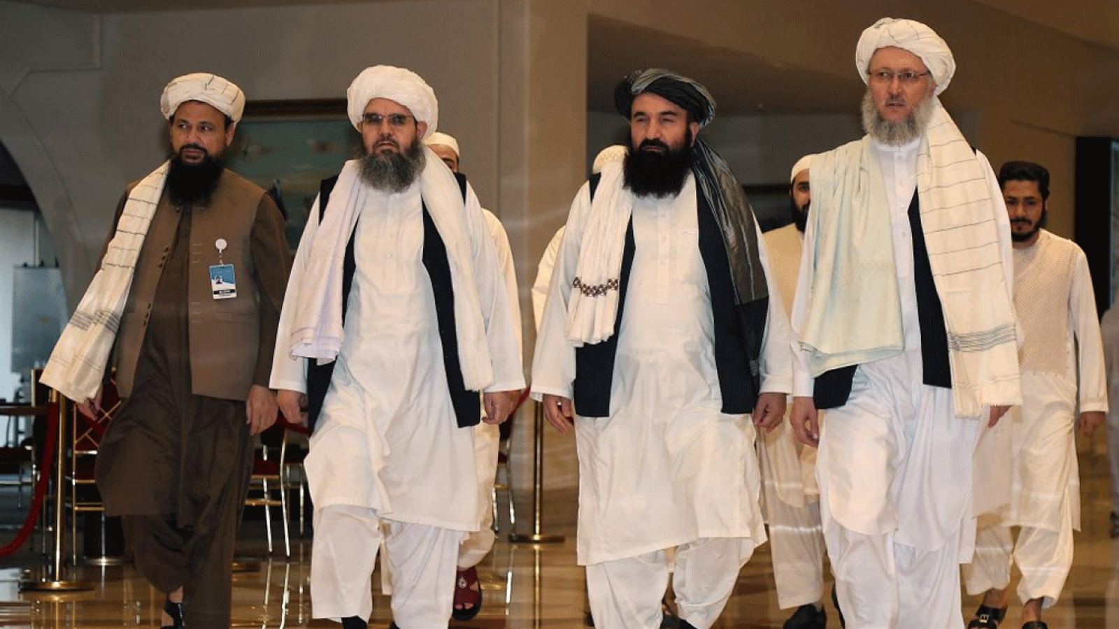 مسؤولو طالبان يسيرون في بهو الفندق خلال المحادثات في العاصمة القطرية الدوحة في 12 آب/ أغسطس 2021