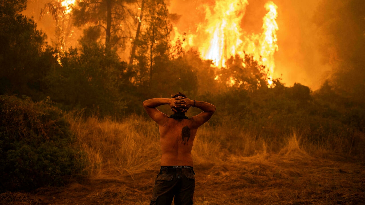 رد فعل أحد السكان المحليين وهو يلاحظ حريقًا كبيرًا خلال محاولة لإطفاء حرائق الغابات التي تقترب من قرية بيفكي في إيفيا، ثاني أكبر جزيرة في اليونان، في 8 آب/ أغسطس 2021.