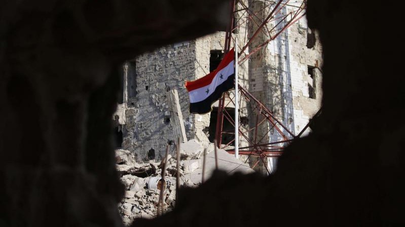 علم النظام السوري وسط مبان مدمرة في درعا البلد في 12 تموز 2018