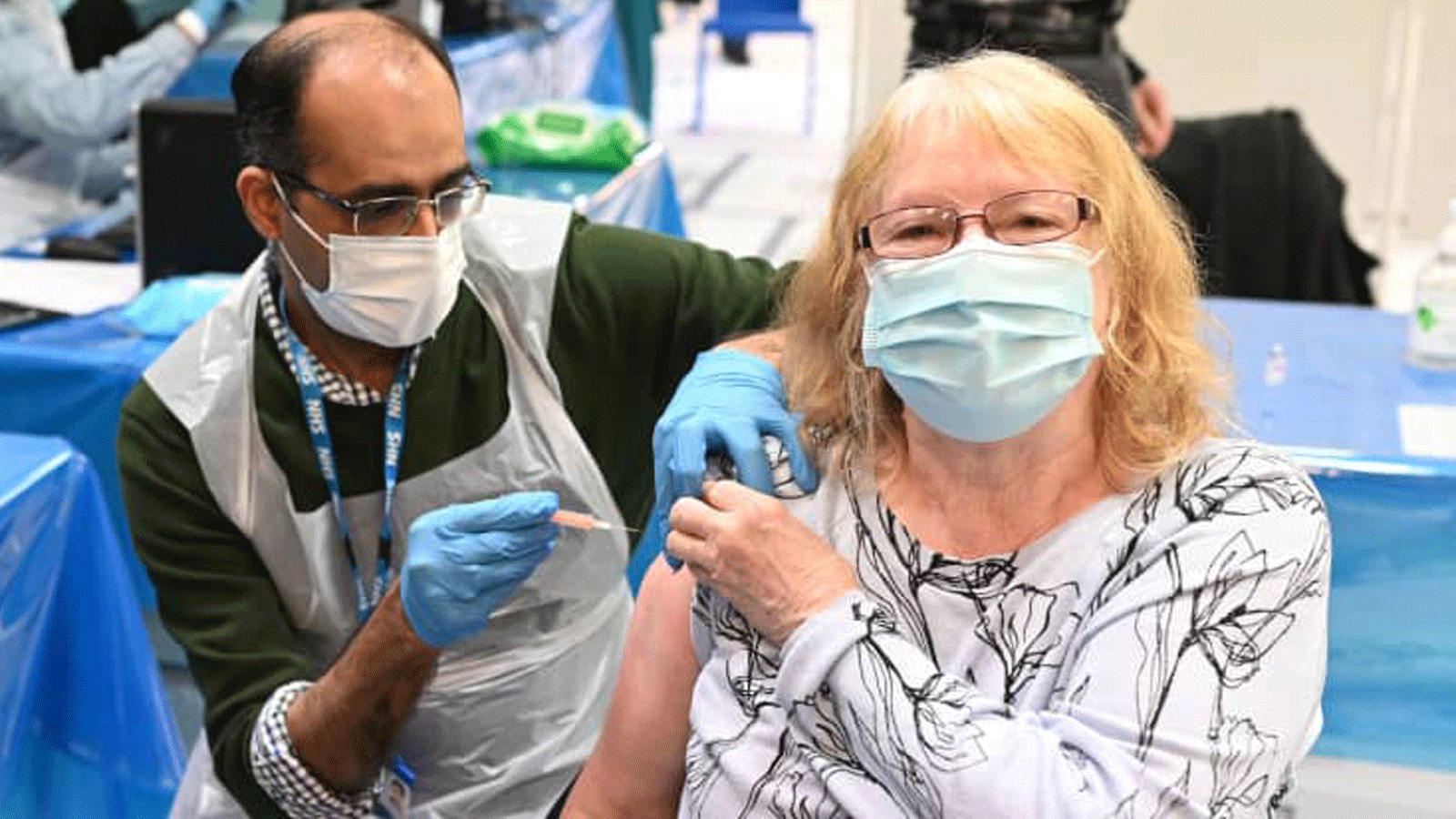 يقدم الصيدلاني مرتضى عبد الكريم (يسار) جرعة من لقاح AstraZeneca / Oxford Covid-19 لسيدة في مركز تطعيم مؤقت يعمل به الصيادلة ومساعدي الصيادلة في مركز العباس الإسلامي في برمنغهام، ويست ميدلاندز في 4 شباط/ فبراير، 2021.