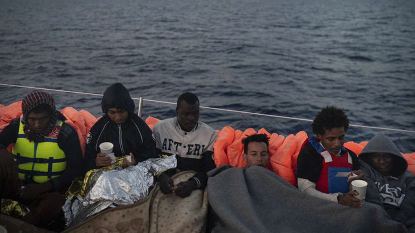 صورة تُظهر لاجئين ومهاجرين يجلسون في سفينة بعد يوم من إنقاذهم أثناء محاولتهم مغادرة ليبيا. 7 مايو / أيار 2018