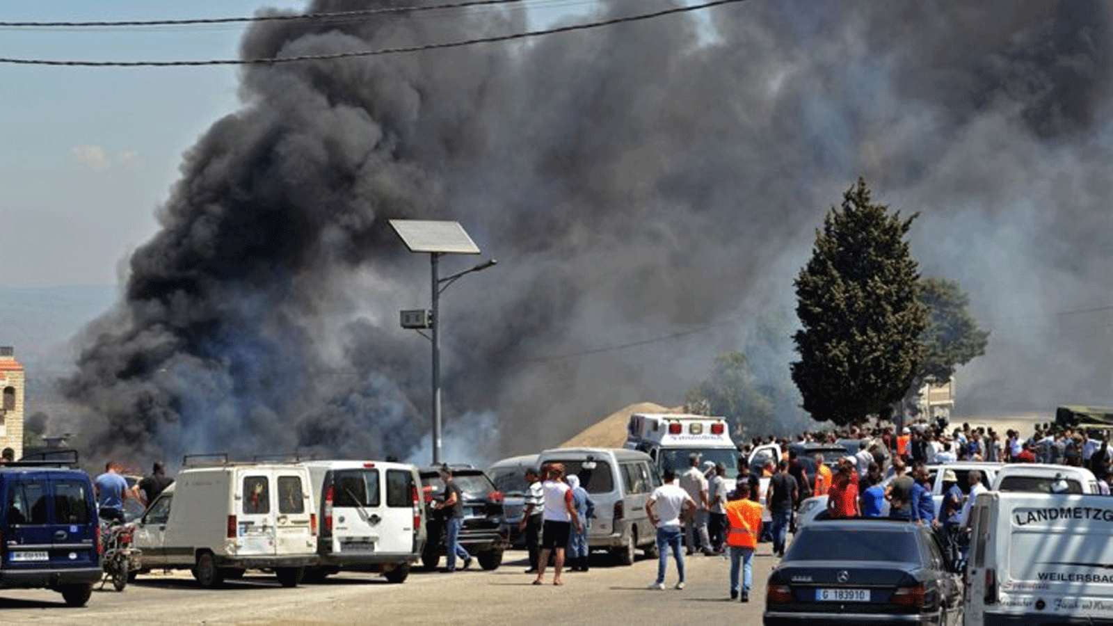 الناس يتجمعون بينما يتصاعد الدخان حيث انفجر خزان الوقود، في قرية التليل في منطقة عكار شمال لبنان. الأحد 15 آب/ أغسطس 2021