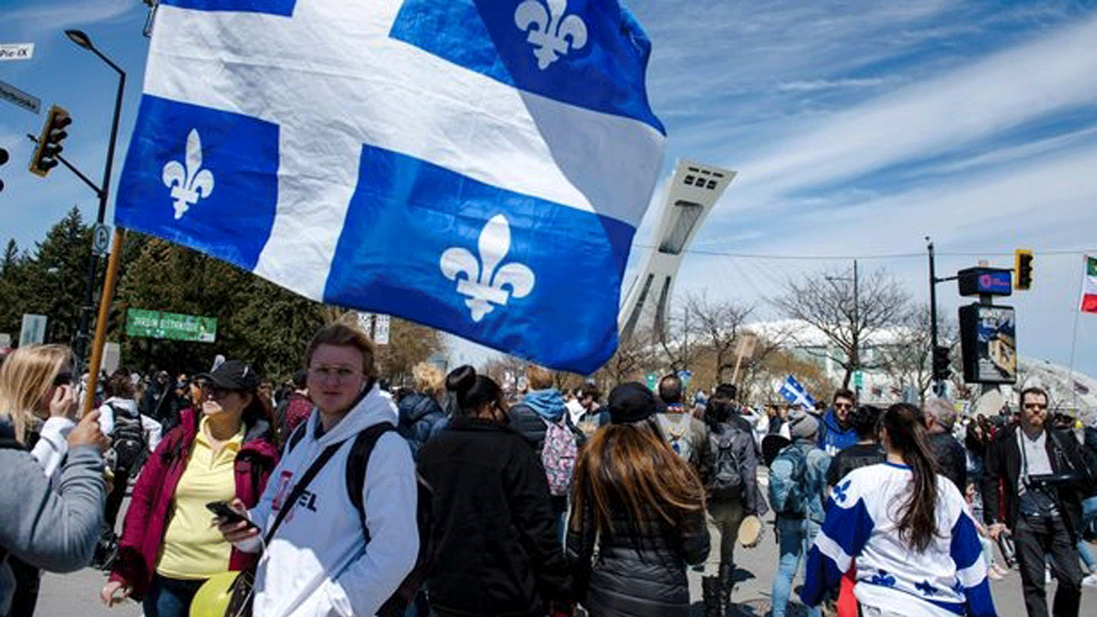 متظاهرون يسيرون أمام الاستاد الأولمبي في مونتريال إحتجاجًا على قيود كوفيد-19. بتاريخ 1 أيار/ مايو 2021.
