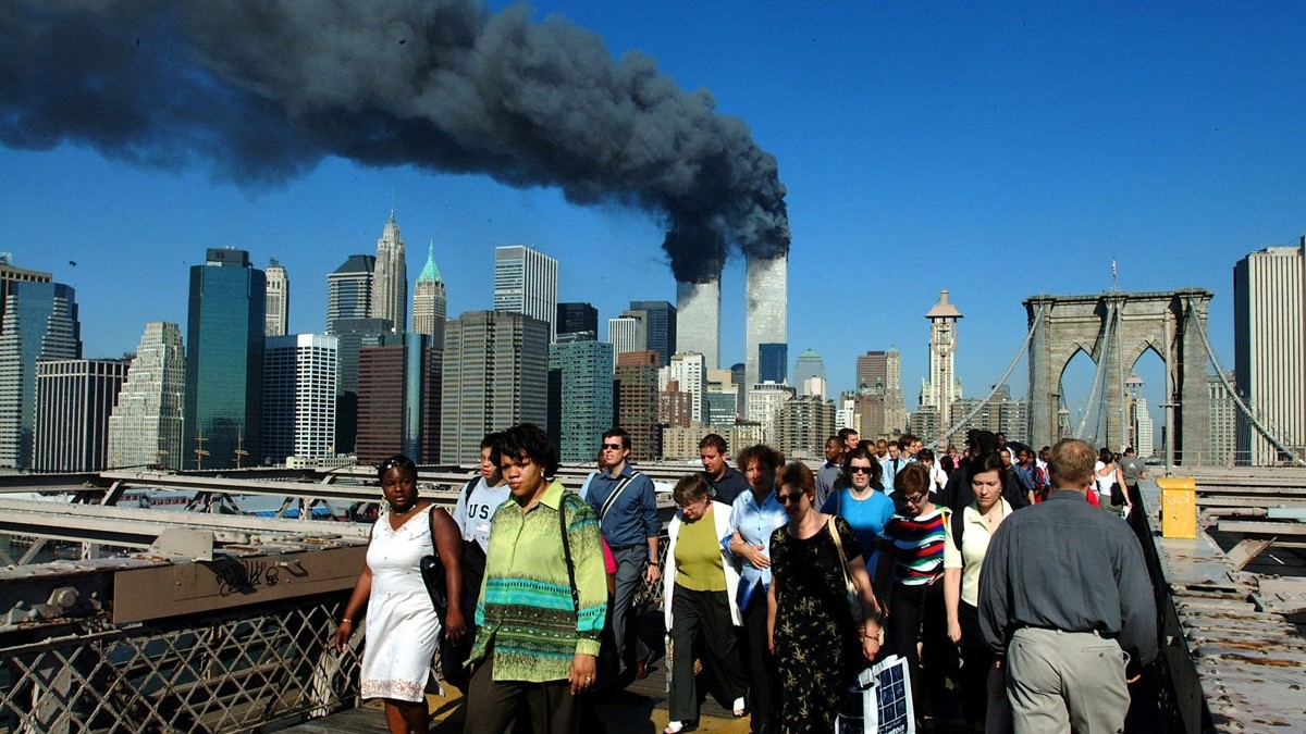 مشاة يعبرون جسر بروكلين بعيدًا عن مركز التجارة العالمي المحترق في 11 سبتمبر 2001