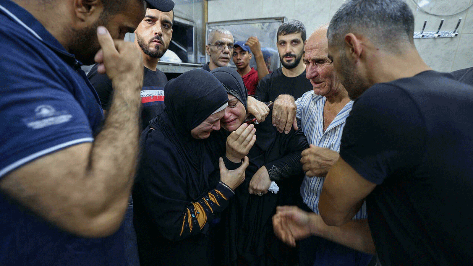 أصدقاء وأقارب يواسون والدة أحد الفلسطينيين الذين قُتلوا في اشتباكات مع القوات الإسرائيلية في مخيم جنين للاجئين شمال الضفة الغربية المحتلة، في مشرحة مستشفى جنين. بتاريخ 16 آب/ أغسطس 2021