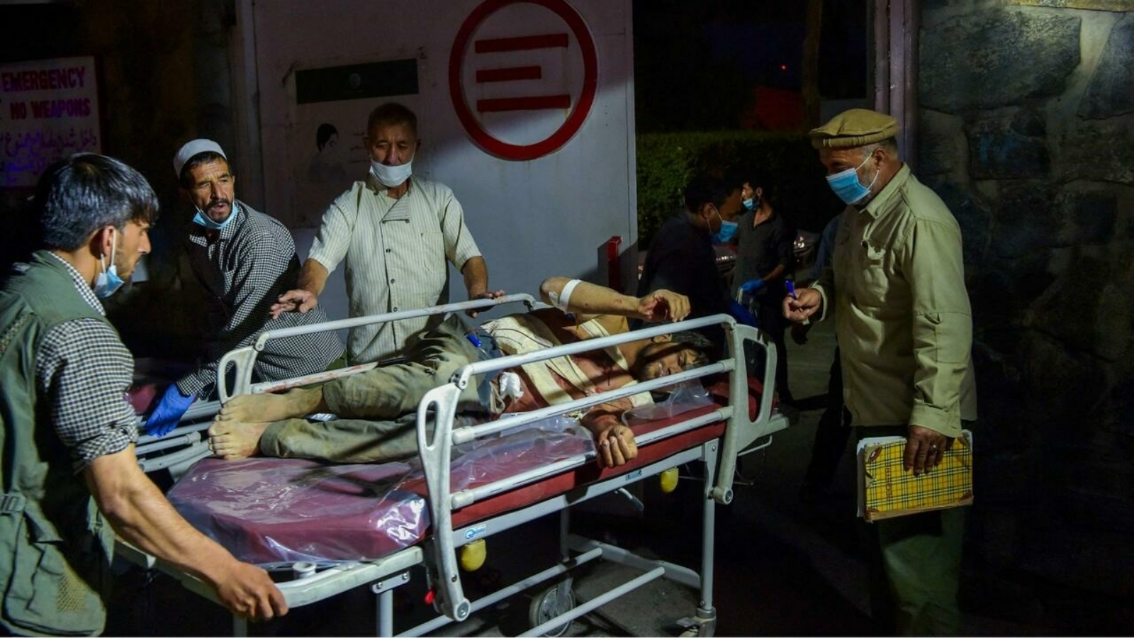 طاقم طبي ينقل رجلاً مصابًا لتلقي العلاج بعد انفجارين قويين أسفرا عن مقتل ستة أشخاص على الأقل، خارج مطار كابول في 26 آب/ أغسطس 2021.