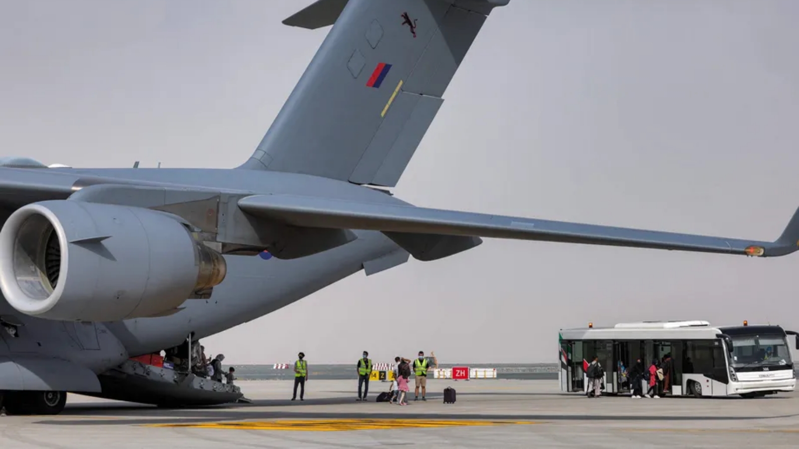 أشخاص ينزلون من طائرة نقل عسكرية تابعة للقوات الجوية الملكية البريطانية تقل أشخاص تم إجلاؤهم من أفغانستان في الإمارات العربية المتحدة. بتاريخ 19 آب/ أغسطس 2021.