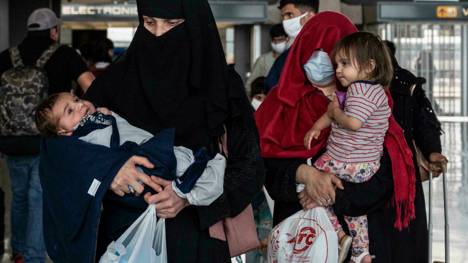 لاجئون من أفغانستان ينتظرون حافلة بعد وصولهم إلى مطار دالاس الدولي في دالاس، فيرجينيا.