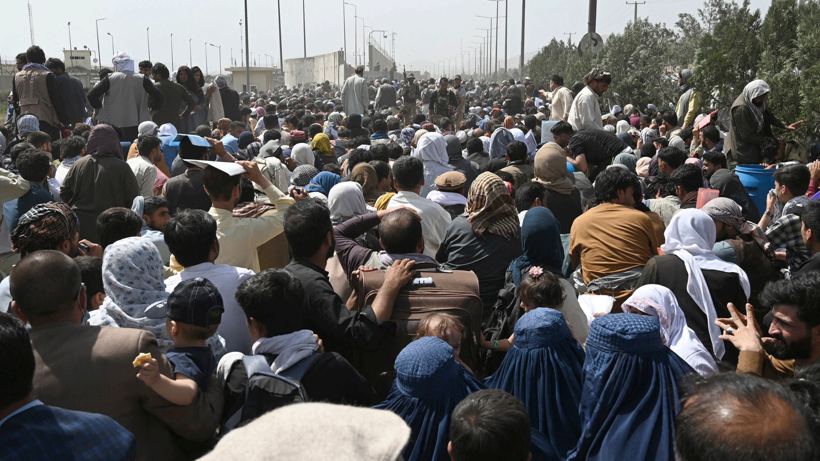 أفغان يحاولون الفرار من البلاد بعد سيطرة طالبان العسكرية. يتجمعون على جانب طريق بالقرب من الجزء العسكري من مطار كابول في 20 آب/أغسطس 2021 