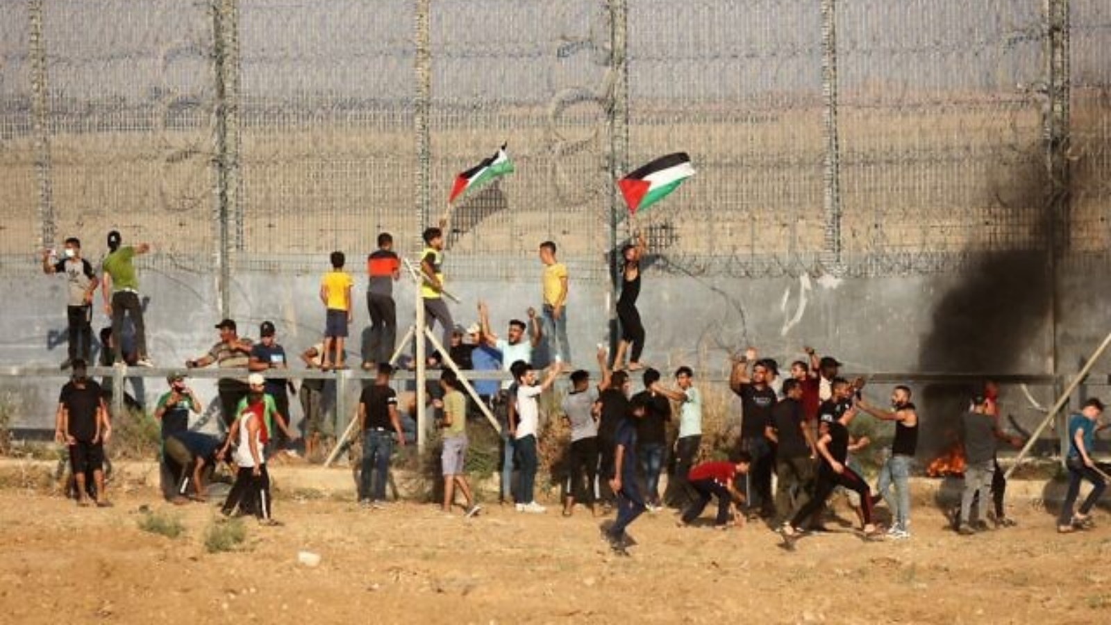 متظاهرون فلسطينيون يرفعون الأعلام الوطنية ويحرقون الإطارات خلال مظاهرة بالقرب من السياج الحدودي مع إسرائيل، شرقي مدينة غزة. بتاريخ 21 آب/ أغسطس 2021
