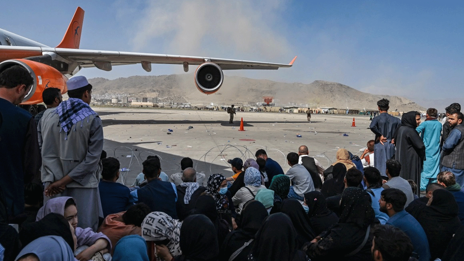أفغانيون يجلسون في انتظار مغادرة مطار كابول بعد أن احتشد الآلاف في المنشأة محاولين الفرار من حكم طالبان