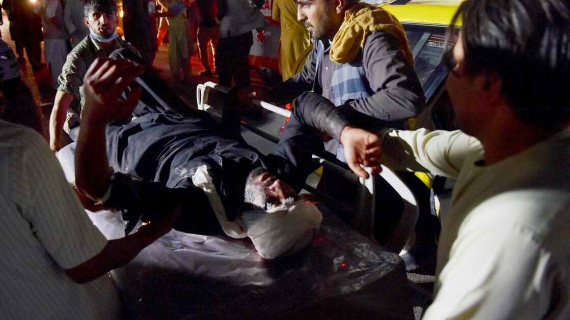 مواطنون أفغان يسعفون جريحًا سقط في أحد انفجاري مطار كابول
