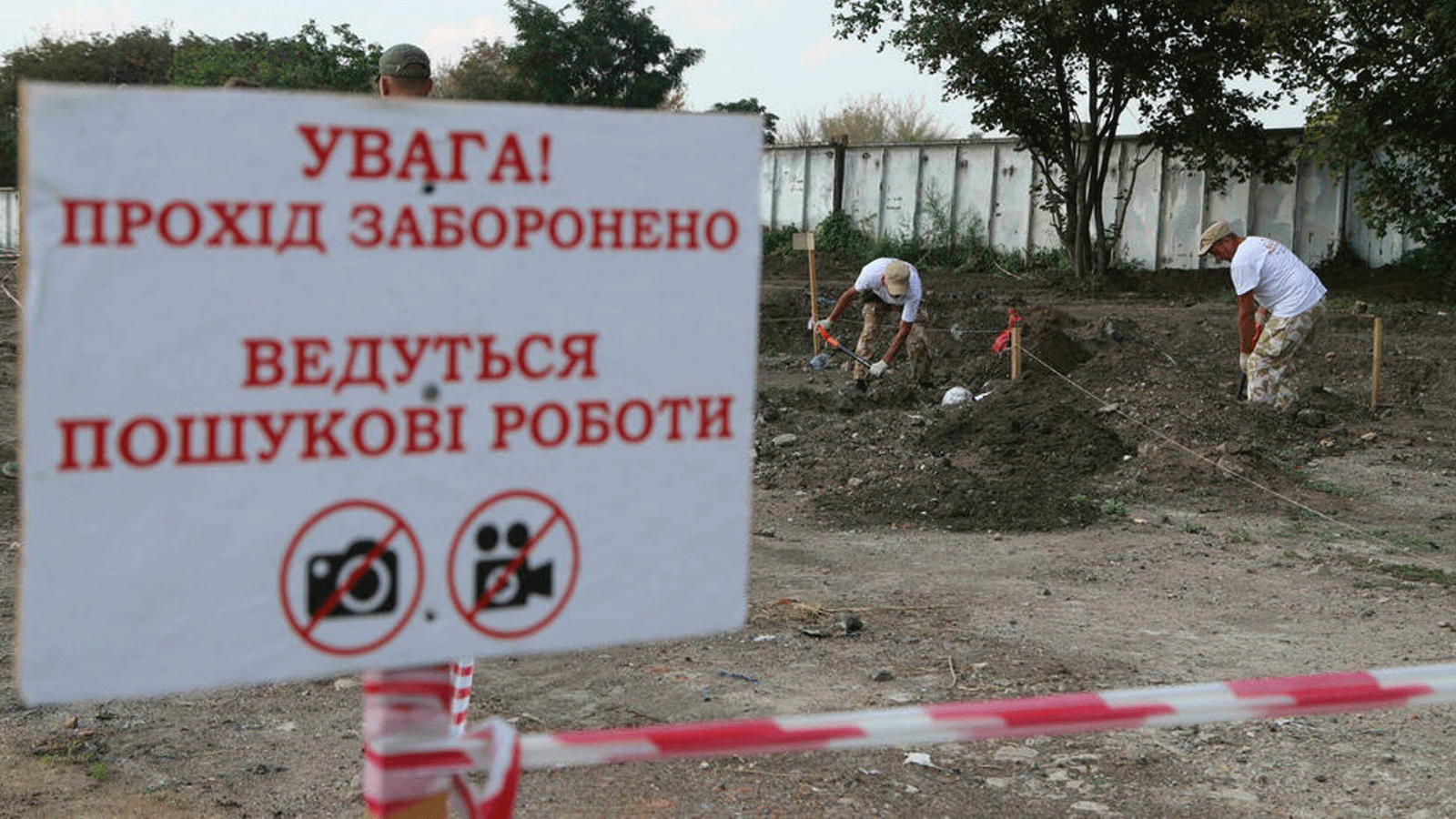 أشخاص يعملون في موقع المقبرة الجماعية التي تم اكتشافها بالقرب من مطار أوديسا في أوكرانيا
