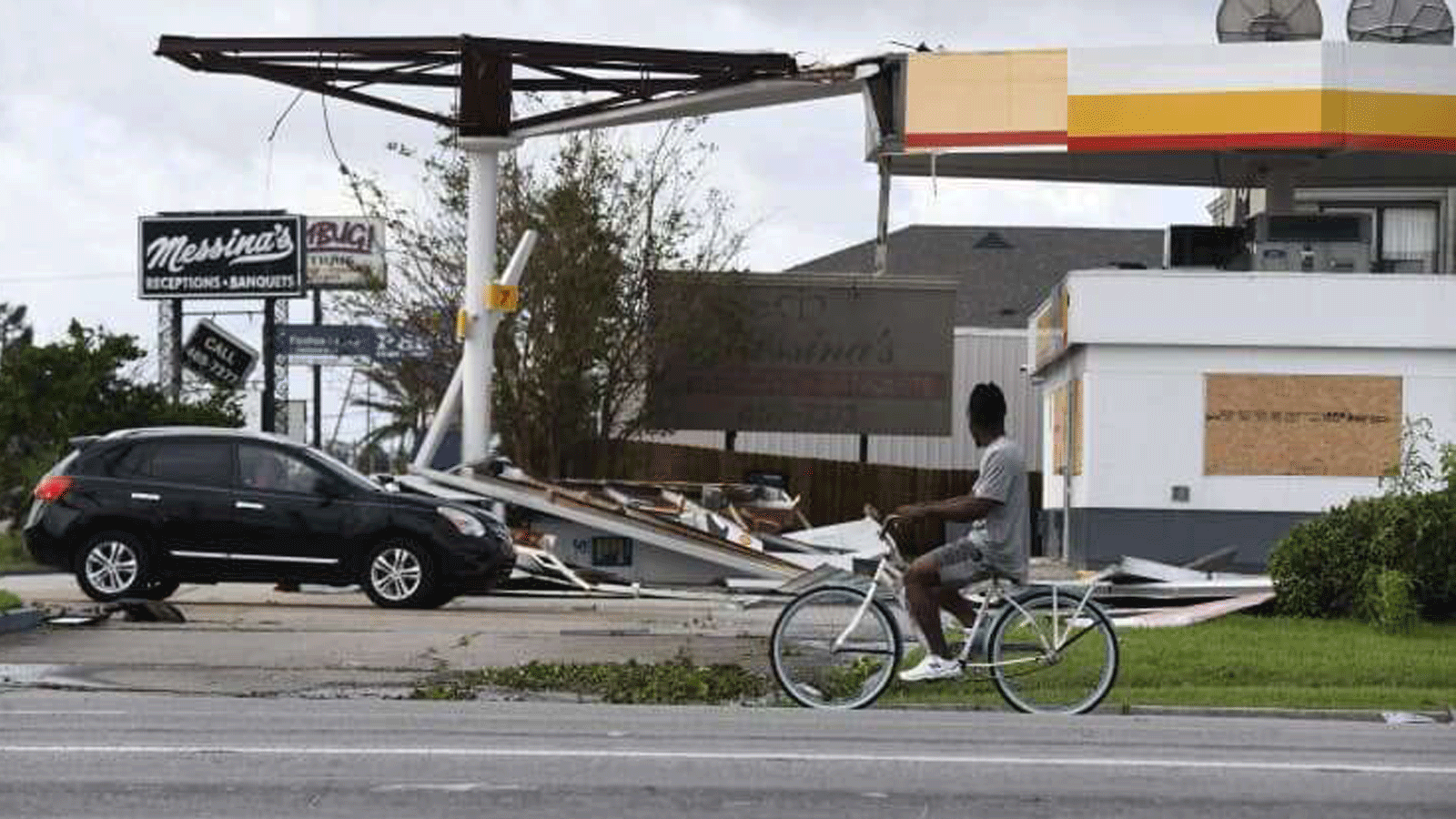 شخص على دراجة يمرّ عبر محطة شل المتضررة جرّاء إعصار إيدا في كينر، لويزيانا. في 30 آب/ أغسطس 2021 