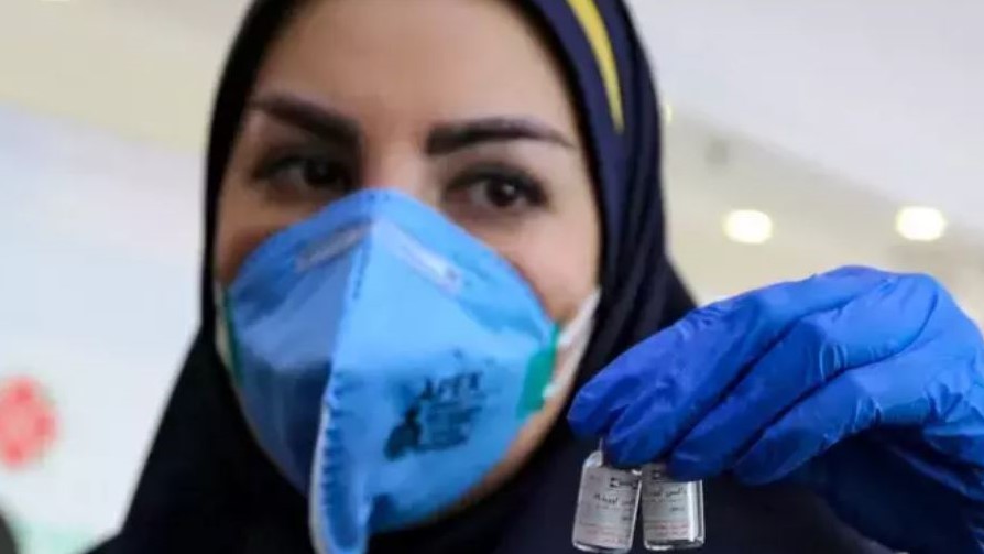 ممرضة إيرانية تحمل جرعيتن من اللقاح ضد كورونا في أحد مراكز التلقيح بطهران